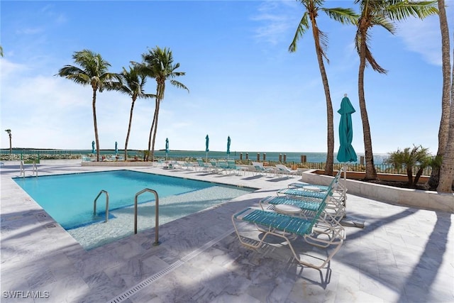 view of swimming pool featuring a water view and a patio