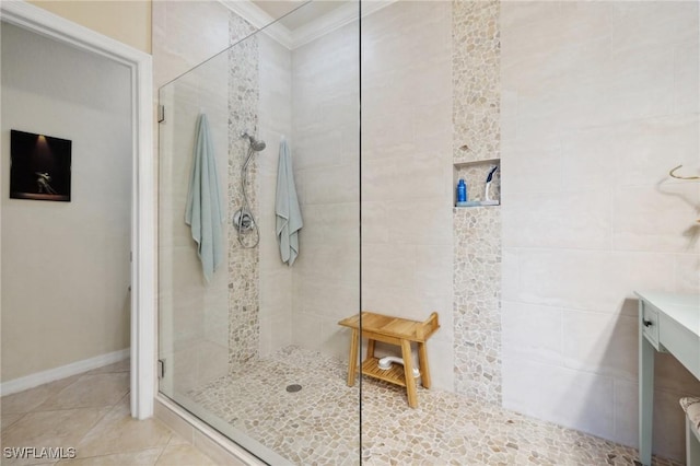 bathroom with tile patterned flooring, tiled shower, baseboards, and ornamental molding