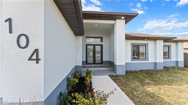 entrance to property with french doors and a lawn