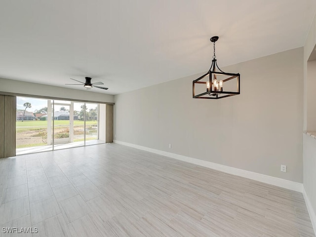 spare room with ceiling fan with notable chandelier