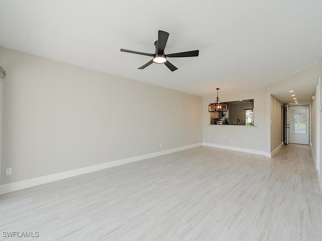 unfurnished living room featuring ceiling fan with notable chandelier