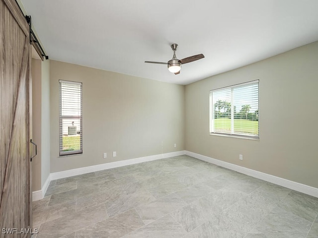 unfurnished room with ceiling fan and a barn door