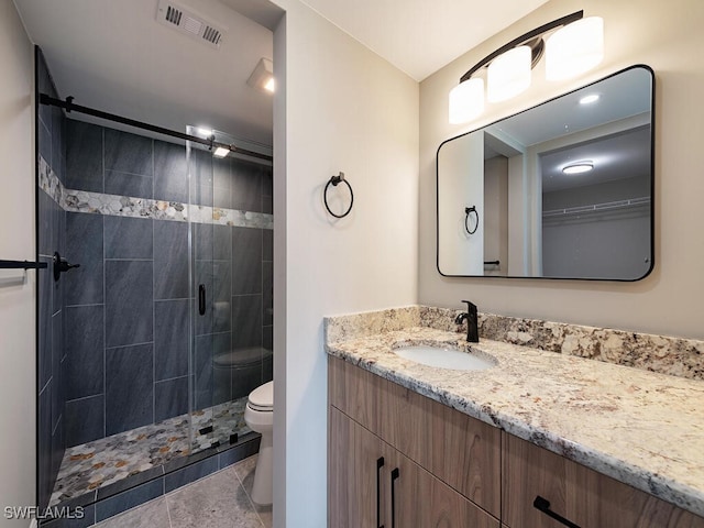 bathroom featuring tile patterned floors, vanity, toilet, and a shower with door