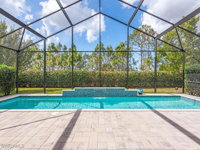 view of pool with pool water feature, a patio area, and glass enclosure