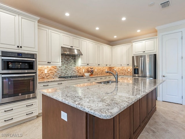 kitchen with sink, a kitchen island with sink, stainless steel appliances, tasteful backsplash, and white cabinets