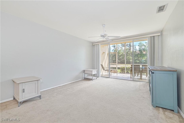 interior space featuring visible vents, baseboards, light colored carpet, and a ceiling fan