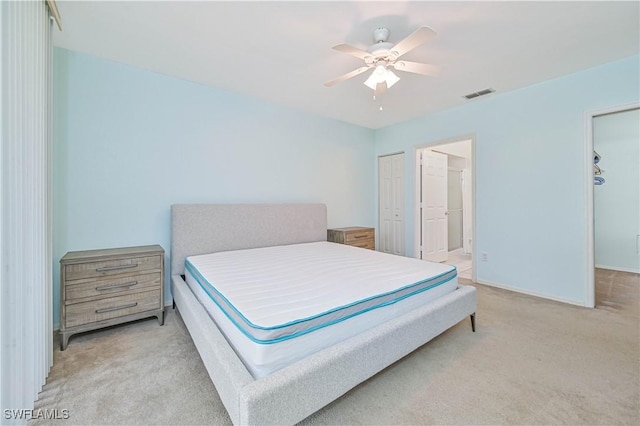 bedroom featuring visible vents, a ceiling fan, a closet, connected bathroom, and light colored carpet