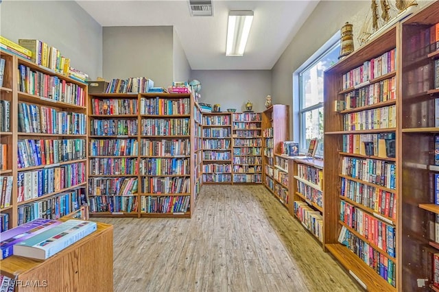 sitting room with visible vents, wood finished floors, and wall of books