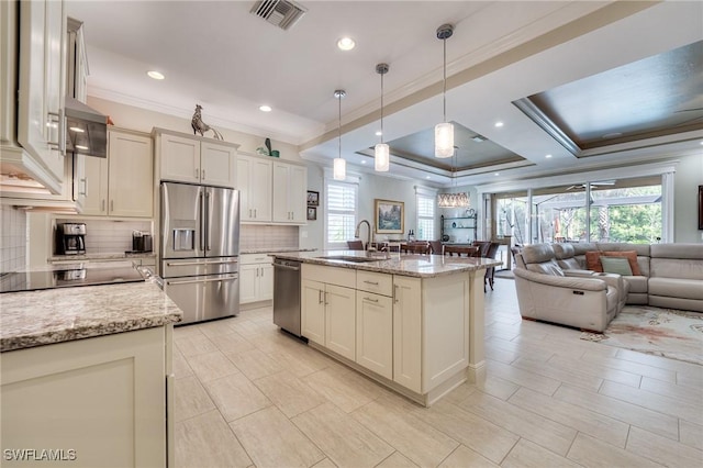 kitchen featuring sink, an island with sink, pendant lighting, stainless steel appliances, and light stone countertops