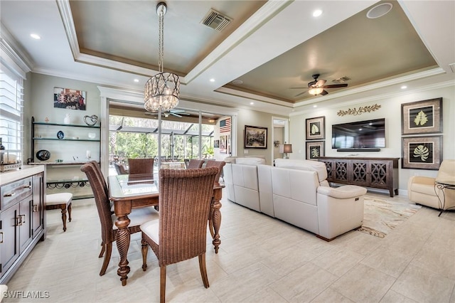 dining area featuring crown molding, ceiling fan with notable chandelier, and a tray ceiling