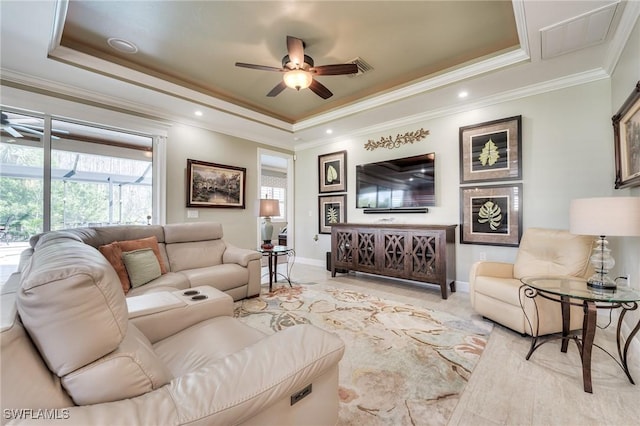 living room featuring ceiling fan, ornamental molding, and a tray ceiling