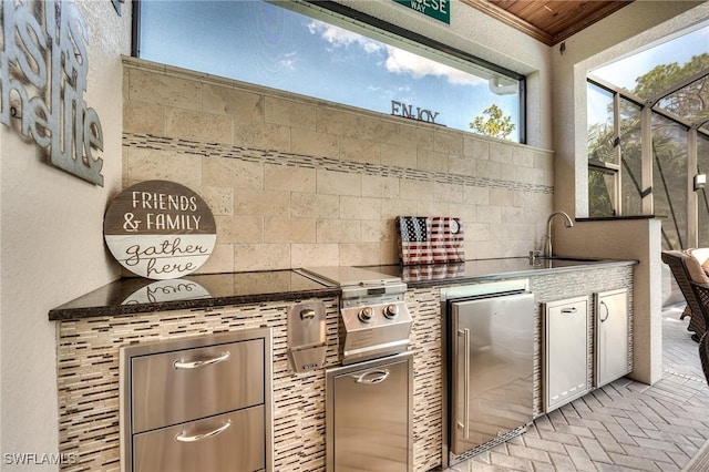 view of patio featuring an outdoor kitchen, a lanai, and sink