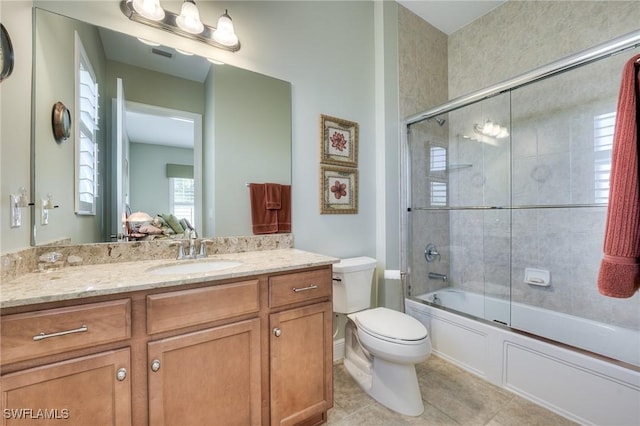 full bathroom with tile patterned flooring, vanity, shower / bath combination with glass door, and toilet