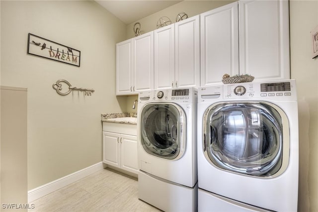 clothes washing area featuring cabinets and washing machine and dryer