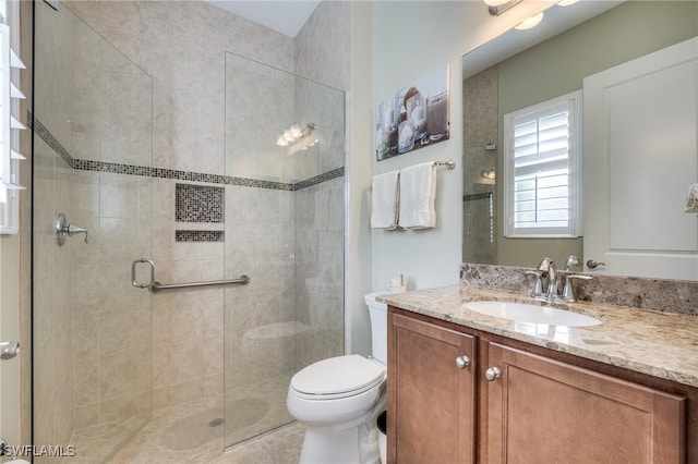 bathroom featuring vanity, a shower with door, and toilet