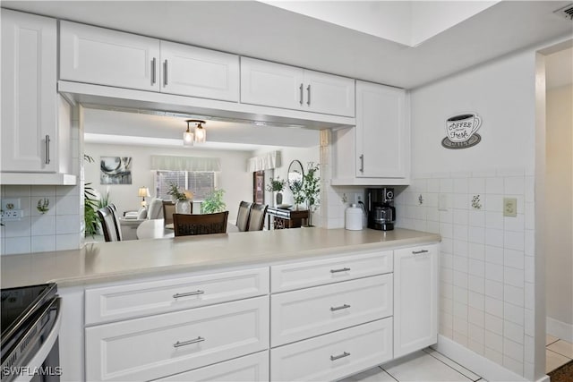 kitchen with electric range, white cabinets, and light tile patterned flooring