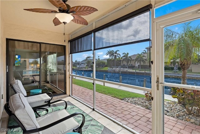 sunroom / solarium featuring ceiling fan and a water view