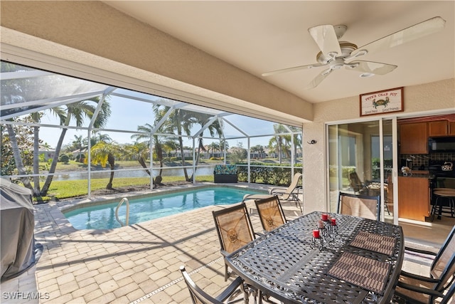 view of pool with a lanai, a patio, ceiling fan, and a water view