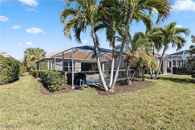 back of house with a lanai and a lawn