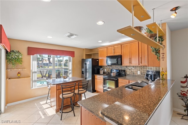 kitchen with sink, a kitchen breakfast bar, kitchen peninsula, decorative backsplash, and black appliances