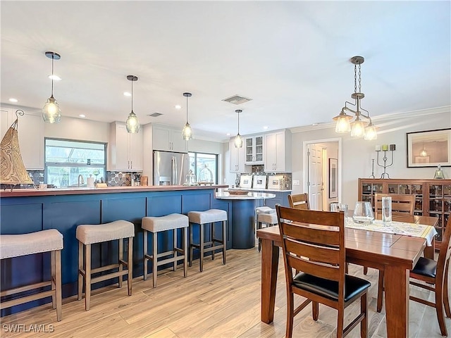 dining area featuring ornamental molding, plenty of natural light, light hardwood / wood-style floors, and sink