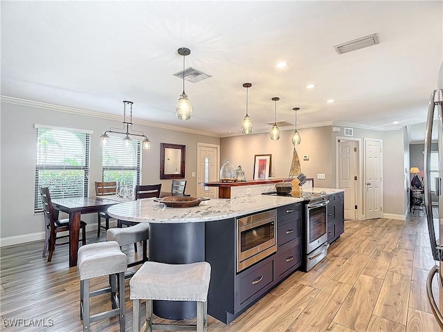 kitchen with a large island, stainless steel appliances, and decorative light fixtures