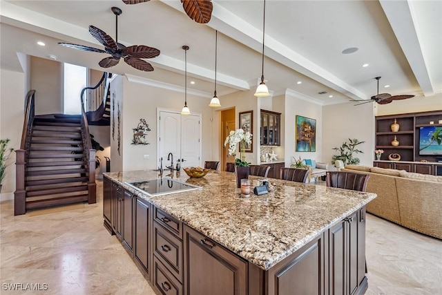 kitchen with a kitchen island with sink, hanging light fixtures, beam ceiling, and ceiling fan