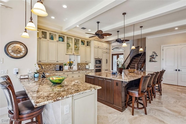 kitchen with light stone counters, a breakfast bar area, cream cabinets, and a kitchen island