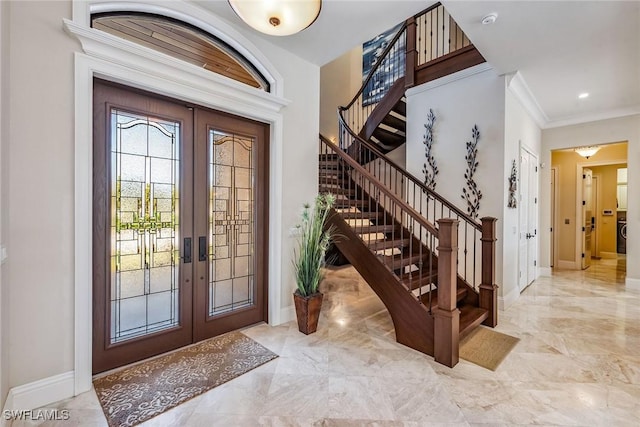 foyer entrance with ornamental molding and french doors