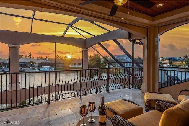 patio terrace at dusk featuring a balcony and ceiling fan