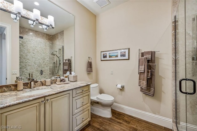 bathroom with wood-type flooring, a chandelier, vanity, walk in shower, and toilet