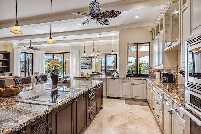 kitchen featuring dark brown cabinets, appliances with stainless steel finishes, light stone countertops, and hanging light fixtures