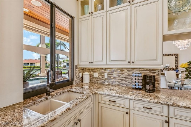 kitchen with tasteful backsplash, light stone countertops, and sink