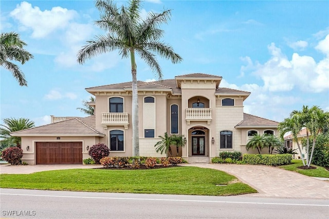 mediterranean / spanish-style home featuring a garage, a front lawn, and a balcony