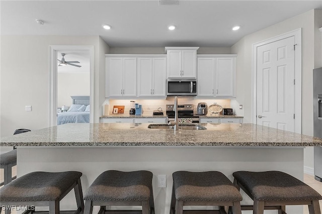 kitchen with white cabinetry, sink, a center island with sink, and appliances with stainless steel finishes