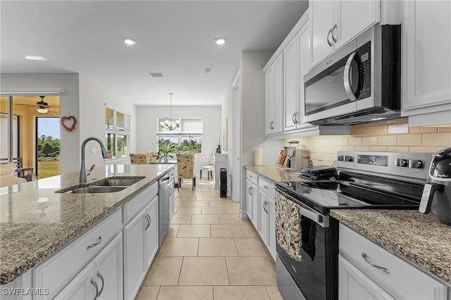 kitchen featuring stainless steel appliances, sink, white cabinets, and decorative light fixtures