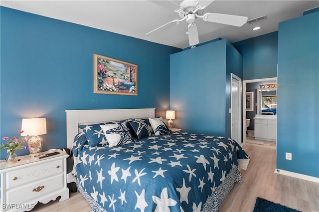 bedroom featuring baseboards, visible vents, wood finished floors, and ensuite bathroom