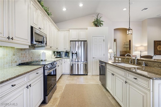 kitchen featuring sink, decorative light fixtures, dark stone counters, stainless steel appliances, and white cabinets