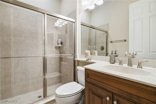 bathroom with vanity, a shower with shower door, and toilet