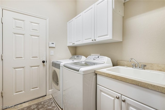 laundry area featuring cabinets, separate washer and dryer, and sink