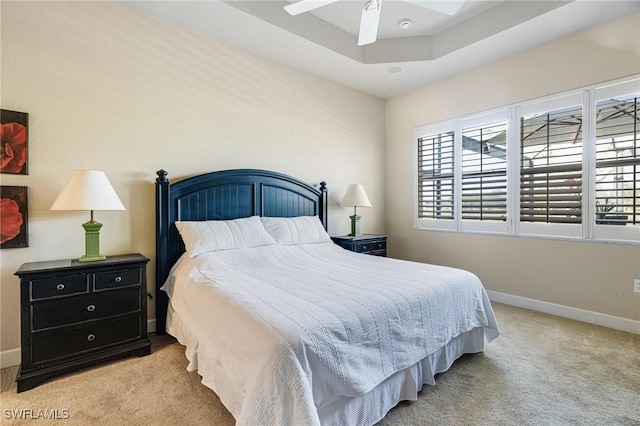 bedroom featuring ceiling fan, a raised ceiling, and light carpet