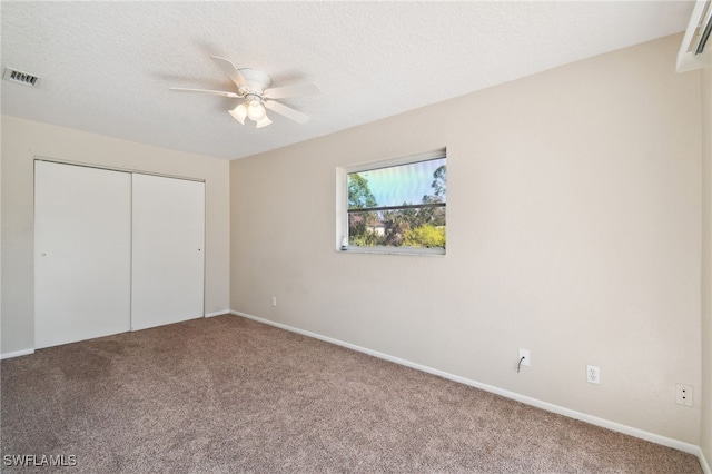 unfurnished bedroom with ceiling fan, a closet, a textured ceiling, and carpet