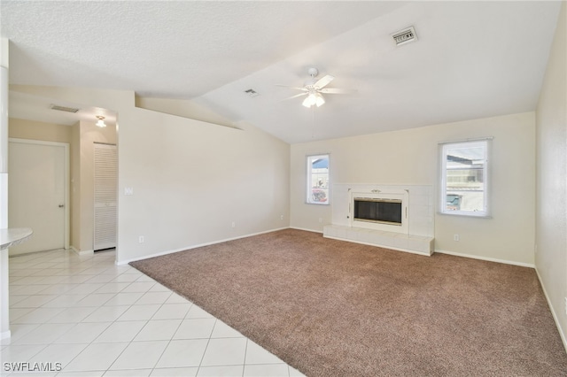 unfurnished living room with plenty of natural light, light colored carpet, lofted ceiling, and a fireplace