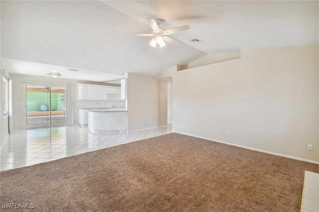 unfurnished living room featuring ceiling fan, light colored carpet, and vaulted ceiling