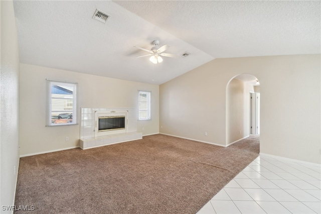 unfurnished living room with a textured ceiling, vaulted ceiling, light colored carpet, and ceiling fan