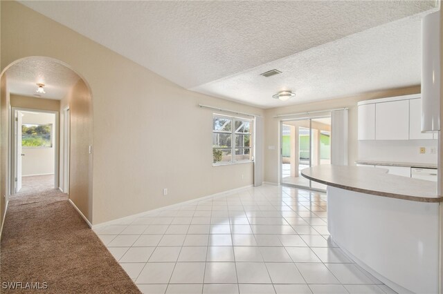 kitchen with white cabinetry, a healthy amount of sunlight, light tile patterned floors, and a textured ceiling