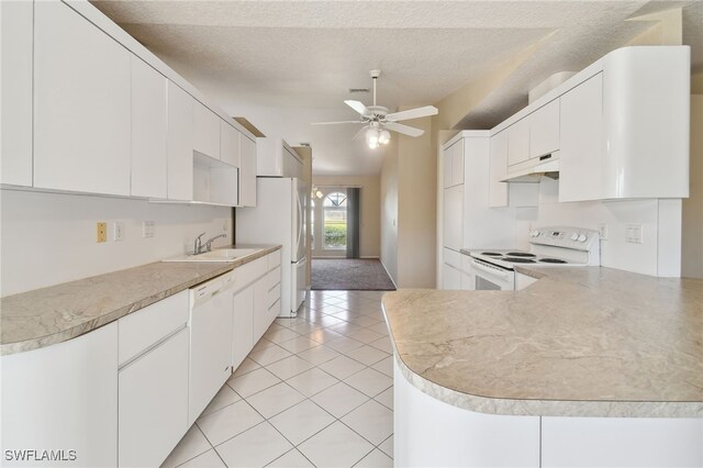 kitchen with light tile patterned flooring, ceiling fan, kitchen peninsula, white appliances, and white cabinets