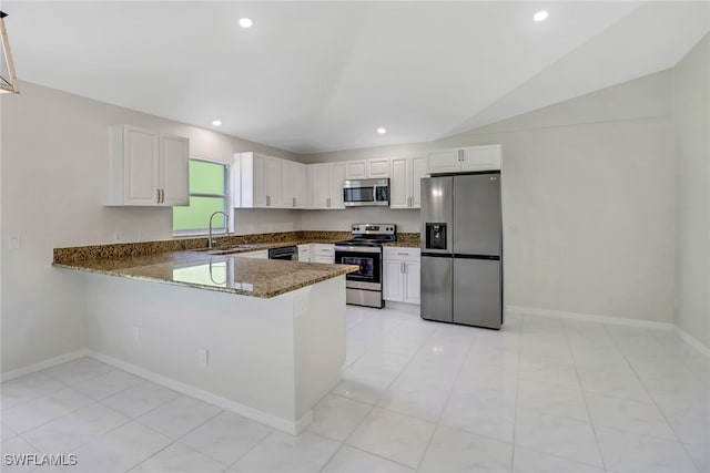 kitchen featuring sink, dark stone counters, kitchen peninsula, stainless steel appliances, and white cabinets