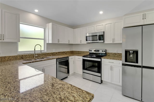 kitchen with stone counters, appliances with stainless steel finishes, sink, and white cabinets