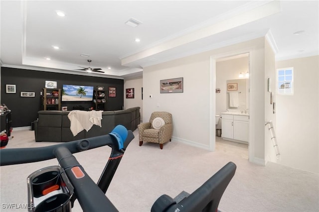 home theater with ornamental molding, light colored carpet, ceiling fan, and a tray ceiling